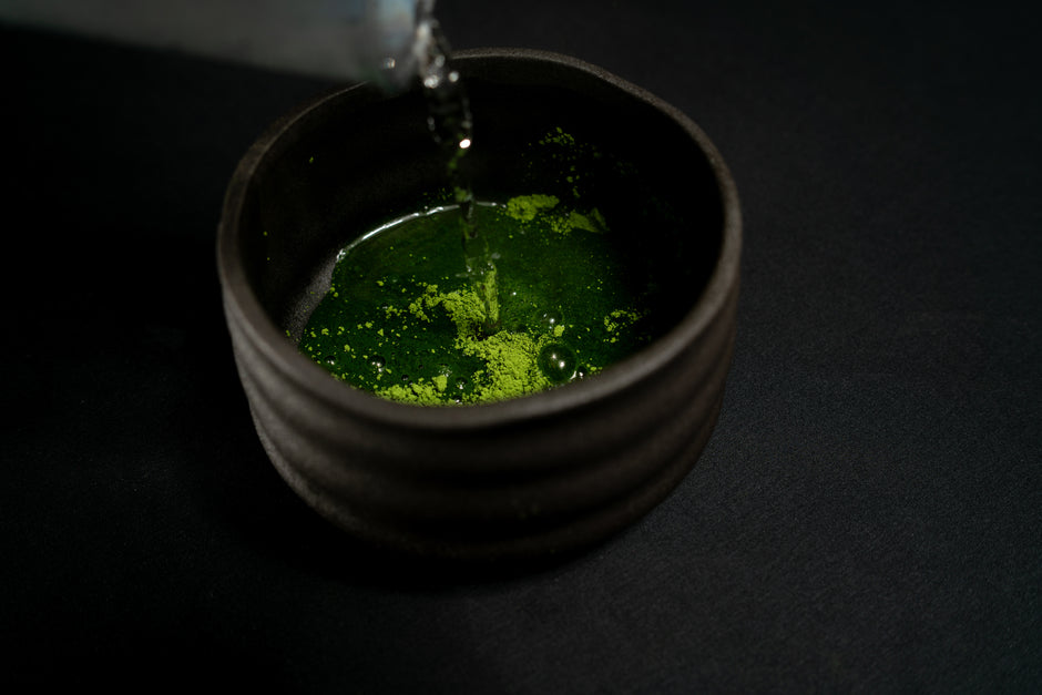 Préparation du thé matcha, l'eau est versée dans le bol chawan avec la poudre de thé matcha bio du japon vert émeraude